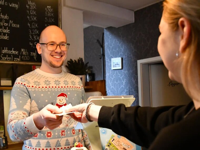 Eine junge Frau bezahlt im Café mit Klimabonus-Scheinen.
